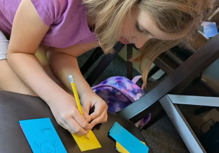 Child writing on colourful wellbeing activity cards during a Positive Pants session