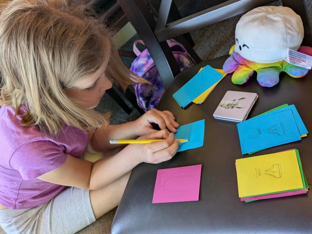 Child writing on colourful feelings cards during a Positive Pants wellbeing activity