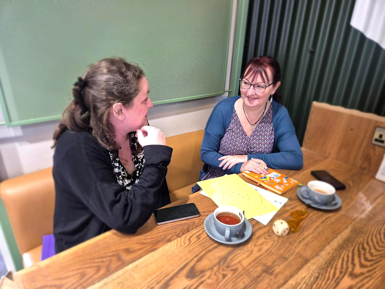 Claire Clements of Positive Pants talking with a parent over worksheets and a cup of tea